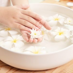 Spa treatment and product for female feet and hand spa. white flowers in ceramic bowl with water for aroma therapy at spa.